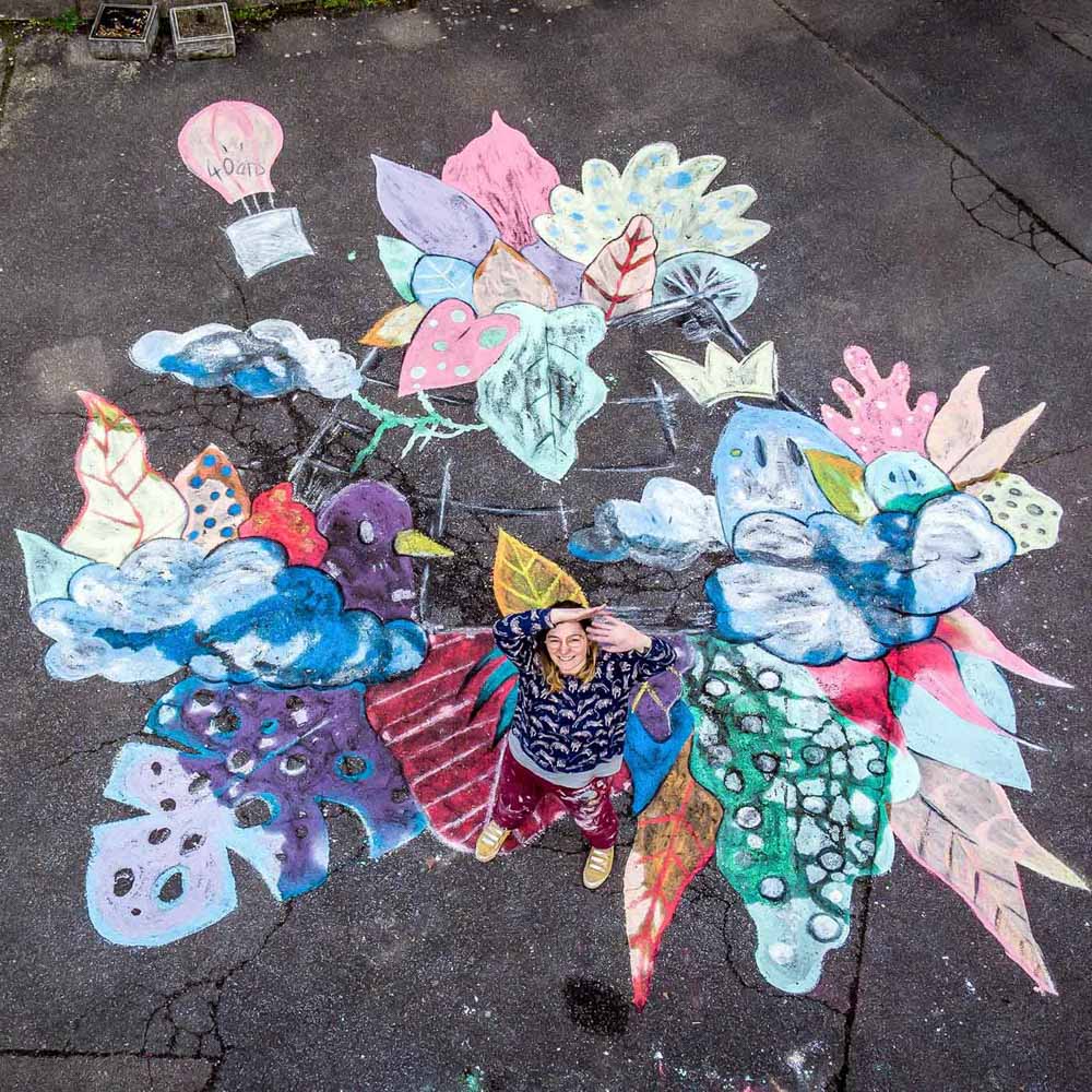 Vue d'ensemble de l'artiste peintre Tsuki dans la lune devant sa fresque colorée, faite à la craie et au sol